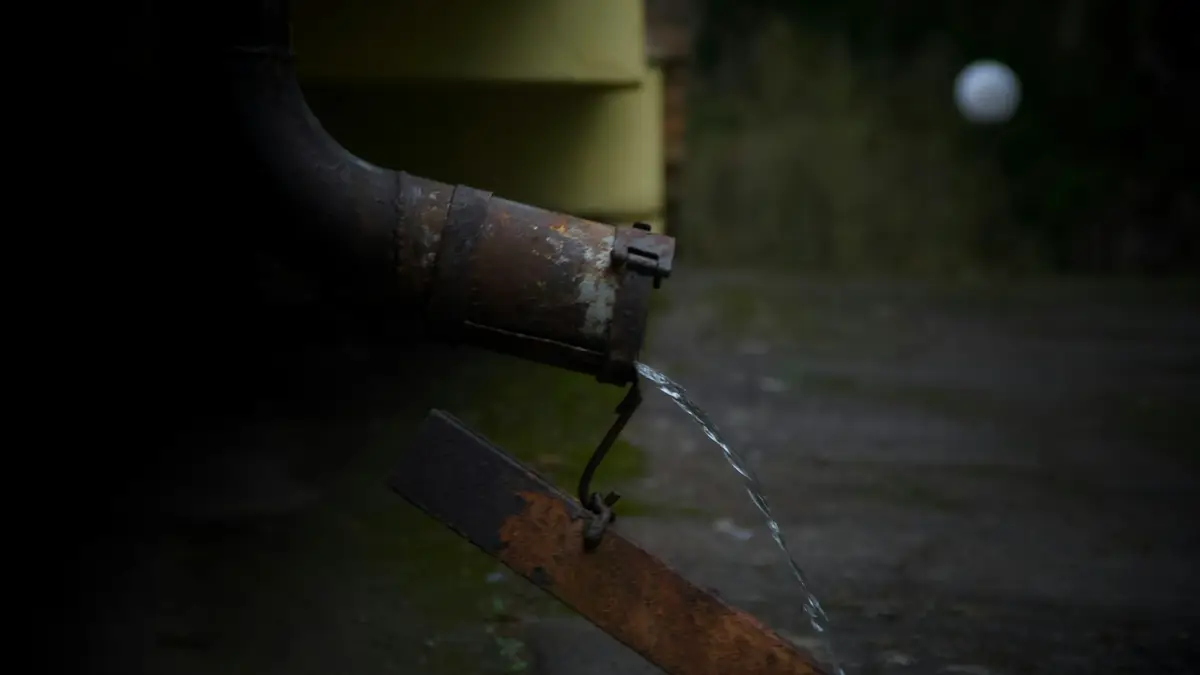 Rusty downpipe outlet pouring rainwater